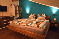 gemütliches türkises Zimmer mit Massivholzmöbeln und Fernseher